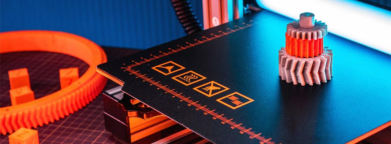 A 3D printed gear on a print bed beside printed components